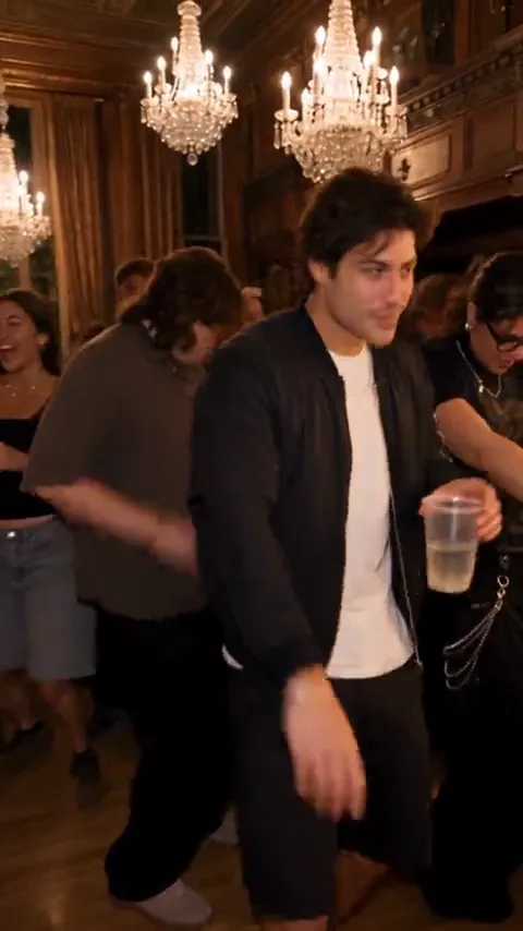 Burning Bridges AI video: a young man in a black jacket raises his cup at a chandelier-lit party